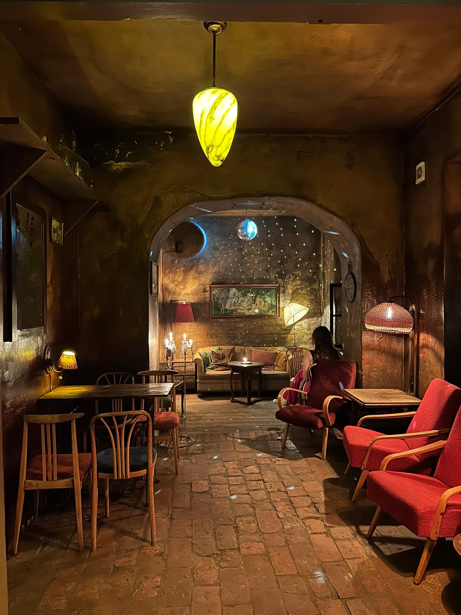 A textured cocktail bar interior with collected furniture and pools of warm light